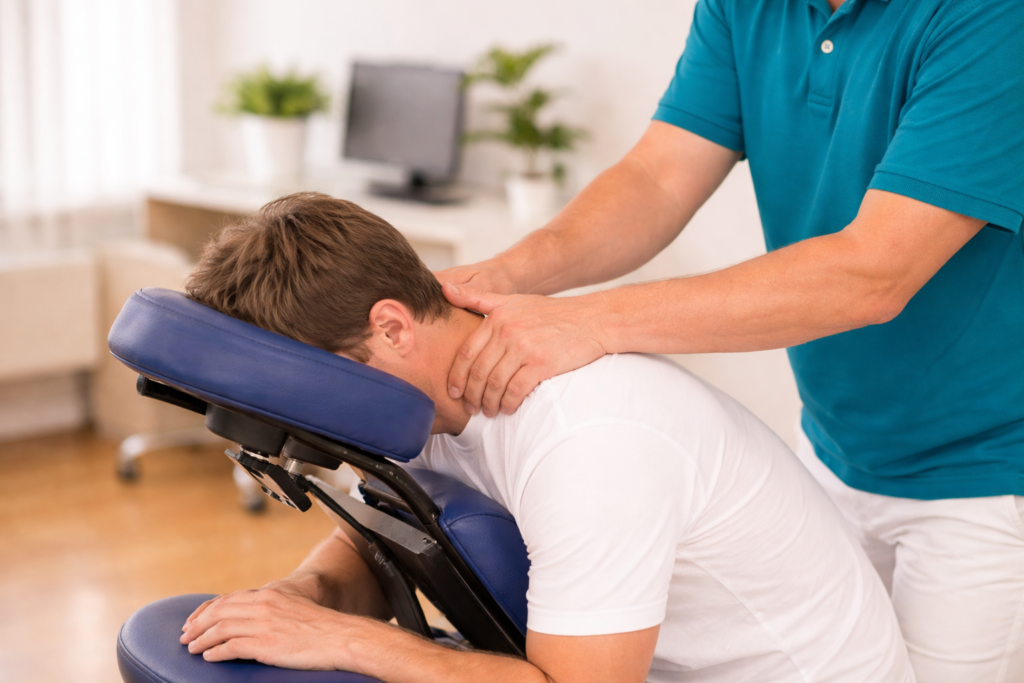 TouchLife mobil am Arbeitsplatz Mann erhält eine entspannende Nackenmassage auf einem mobilen Massagestuhl im Büro, in heller freundlicher Umgebung